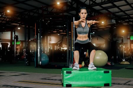 sport woman at fitness gym club doing exercise for legs with box jump and showing muscle bodybuilding, fitness concept, sport conceptの写真素材