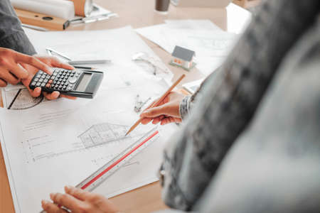 engineers pointing to building on blueprint to drawing design building Project in office, construction concept. Engineer conceptの写真素材