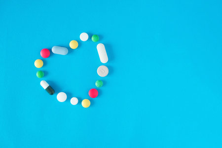 The heart made of colorful tablets and pills on blue background.の写真素材