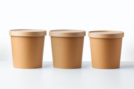 Three brown paper cups with lids placed on white surface. Suitable for various beverage and food concepts.の素材