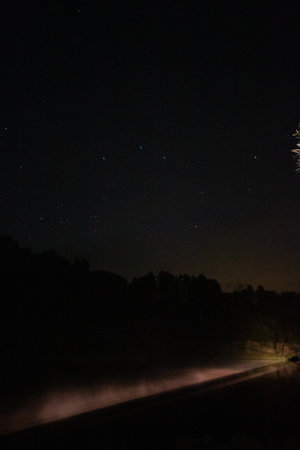 A captivating view of the night sky with stars and a full moon shining over dark fields.