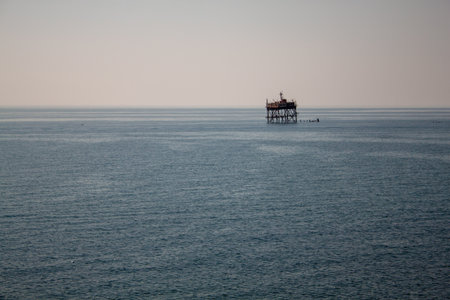 A lone oil rig in the ocean as the sun sets.