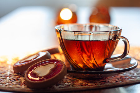 A cup of tea with a heart-shaped cookie on a woven placemat.の写真素材