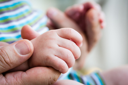 Baby holds hand of his father.の写真素材