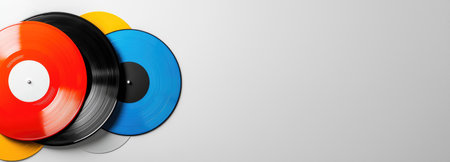 A vibrant arrangement of multicolored vinyl records against a light background, featuring ample copy space for promotional content.の素材