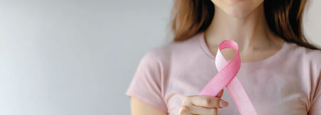 A serene image of a woman holding a pink ribbon, embodying the spirit of Breast Cancer Awareness Month.の素材