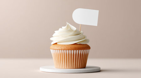 Minimalist food photography of a delicious cupcake with white cream and a blank round topper placed on a wooden pedestal.の素材