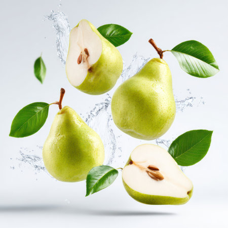 Green pears with leaves splashing in clear water against a clean white background.の素材