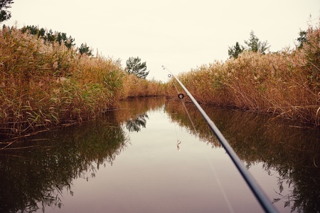 Freshwater Fishing Concept. A rod and line extend out over a tranquil lake with reflections in this concept of fishing, nobody in the frame.の写真素材