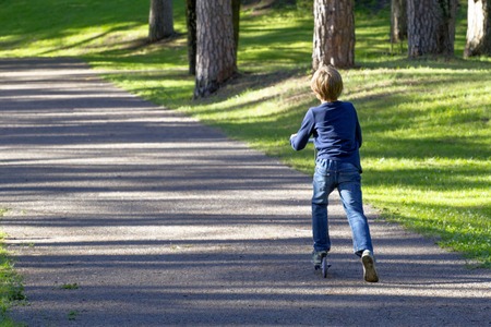Little boy riding with scooter outdoor. Leisure activity