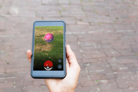 Vilnius, Lithuania - JULY 24, 2016: Person holding mobile phone and playing Pokemon Go game. Pokemon Go is a location-based augmented reality mobile game developed by Niantic for iOS and Android devices.のeditorial素材