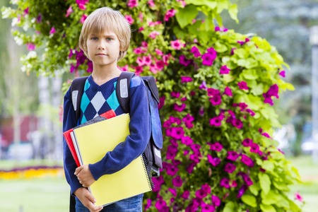 Little schoolboy with books and backpack feeling very excited about going back to school. Education,...