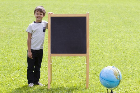 Child boy standing near the blackboard. Outside. Copy space for text or imageの写真素材