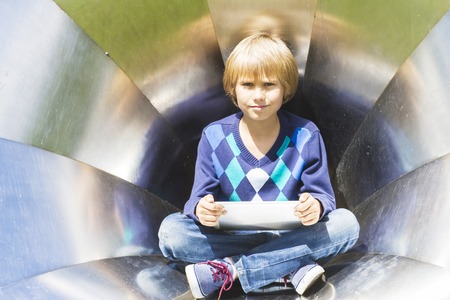 Little boy with tablet PC outdoor. Metal texture background. Back to school, education, learning, technology, leisure conceptの写真素材