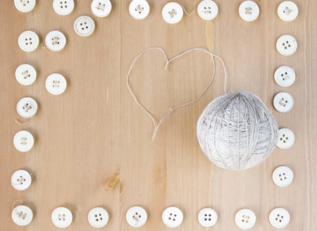 Vintage sewing buttons frame and ball of linen and heart shaped thread. Flat lay, top view.の写真素材