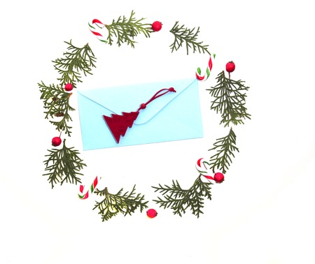 Christmas composition made of envelop and and Xmas decoration with thuja twigs, red wild rose fruits around on white background. Top view, flat lay. Winter holidays conceptの写真素材