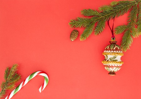 Christmas frame on red background. Green fir branches, Xmas decoration and candy cane. Top view, flat lay. Copy space for text. textWinter holidays conceptの写真素材