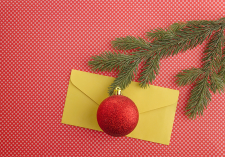 Christmas composition with fir tree branch, cones and yellow envelope on red background. Top view,...