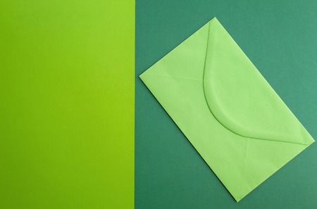 Green envelope on colourful greenery background. Top view. Close up. Minimal conceptの写真素材