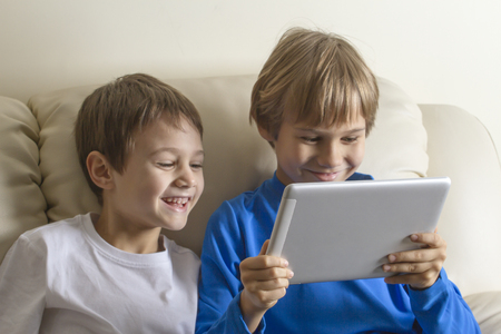 Children with tablet PC. Boys looking at screen, smiling and playing games or watching video. People education learning technology leisure conceptの写真素材