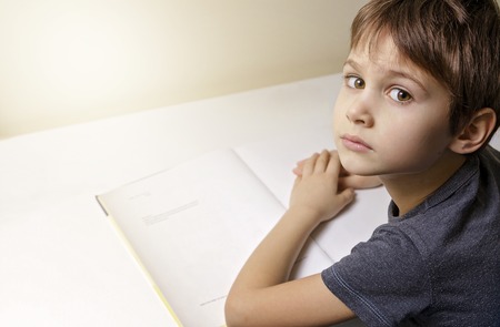 Little boy reading. Child sitting at the desk home.