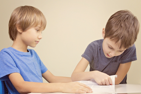 Kids reading a book. Little boy practice reading with his brother.の写真素材