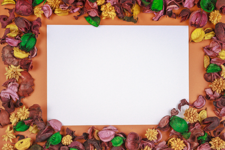 White paper piece surrounded by dried flowers and leaves frame. Top view, flat lay. Copy space for textの写真素材