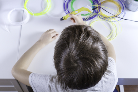 Child creating with 3D printing pen. Boy making new item. Creative, technology, leisure, education...