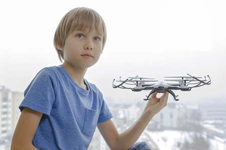 Child with drone against window at home. Technology, leisure toys conceptの写真素材