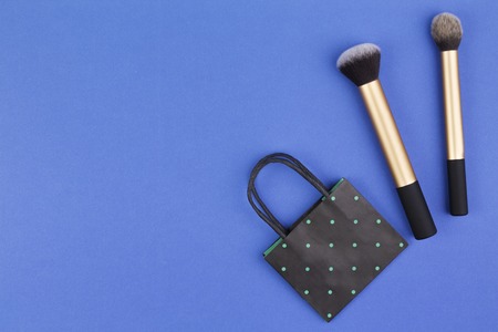 Make up brushes with black polka dot paper shopping bag on blue backgroundの写真素材