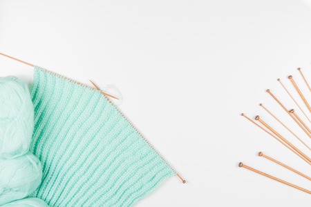 Balls of yarn and knitting and different size knitting needles on white background