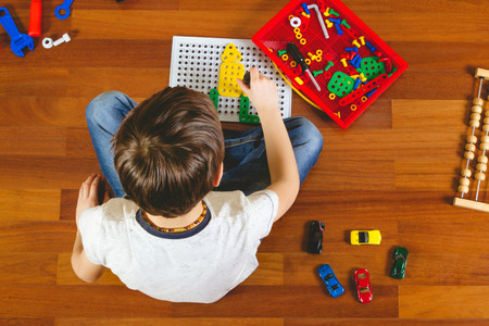 Child playing with toys tool kit while sitting on the floor in his room.Top viewの写真素材