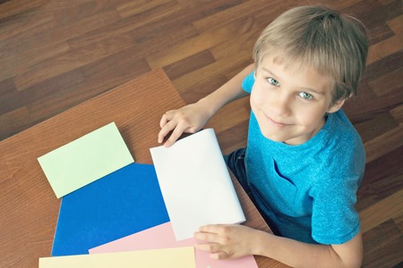 Boy makes greeting card using colored paperの写真素材