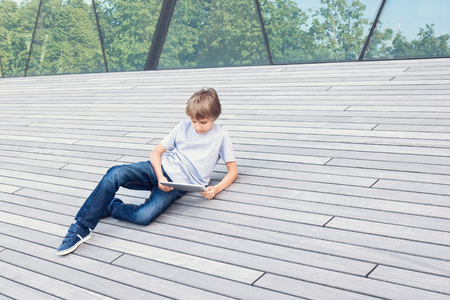 Kid with tablet computer relax in the city at sunny dayの写真素材