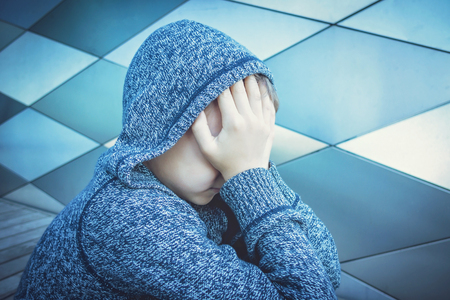 Sad, lonely, unhappy, disappointed child holding head with handsの写真素材