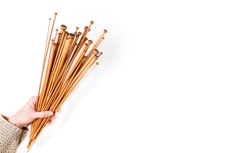 Brown wooden knitting needles in woman hand on white background. Top viewの写真素材