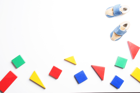 Colorful wooden blocks and baby shoes on white backgroundの写真素材