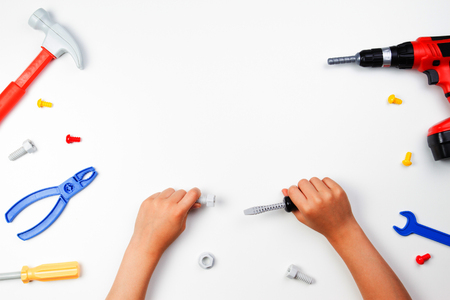 Top view on childs hands with colorful toys tools on the white background.の写真素材