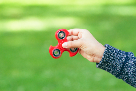 Red fidget spinner fidgeting in boys handの写真素材