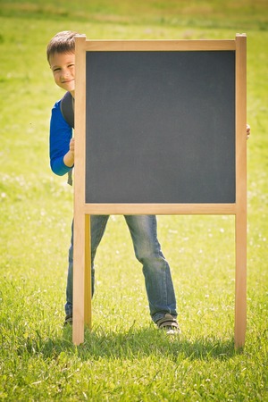 School kid holding blackboard outdoor. Education, back to school conceptの写真素材