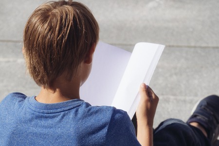 Schoolboy studying, reading book outdoorsの写真素材