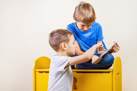Children playing on tablet at homeの写真素材