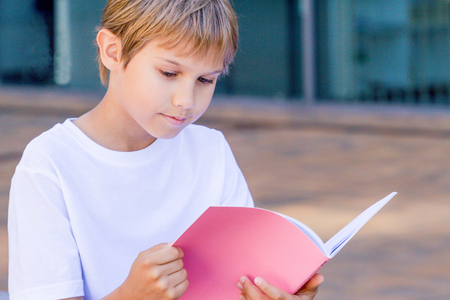 Schoolboy reading books. Kid doing homework outdoors. Back to school concept.の写真素材