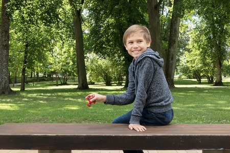 Child sitting on the grass and playing with spinnerの写真素材