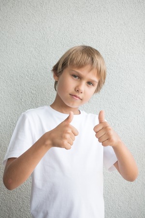 Child with thumbs up over grey backgroundの写真素材