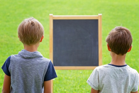 Two boys standing by a blackboard outdoorsの写真素材