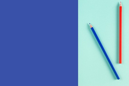 Red and blue colored pencils on blue color backgroundの写真素材