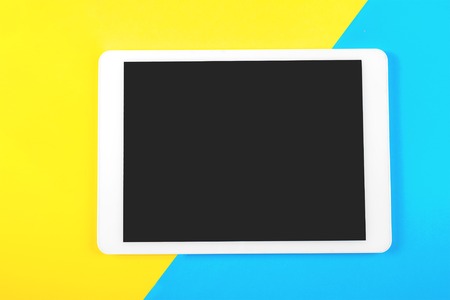 Digital tablet computer on blue and yellow background. Top view.の写真素材