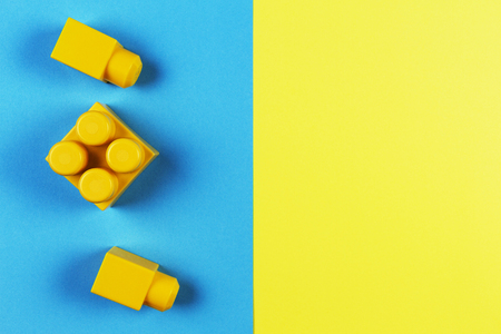 Yellow plastic construction blocks on yellow and blue background