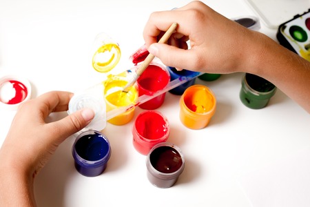 Top view childs hands drawing gouache over white tableの写真素材